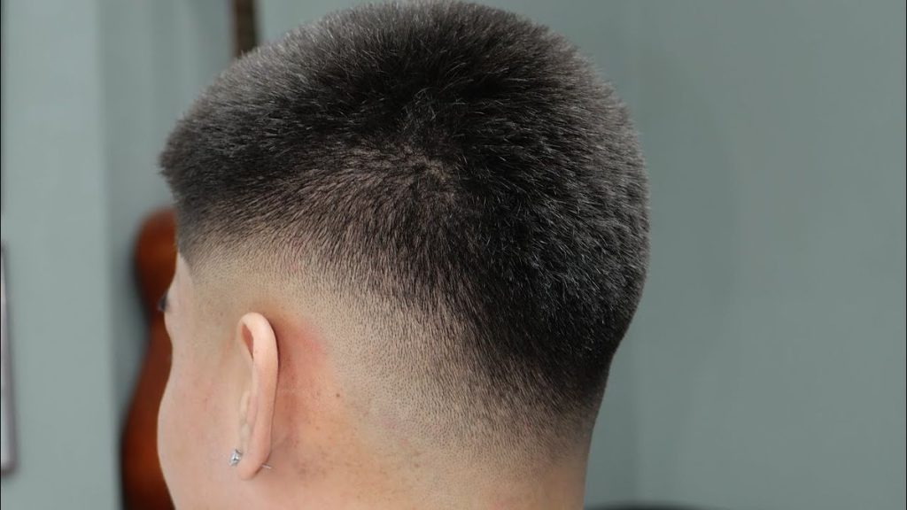 Man sporting a high fade 9 guard buzz cut, featuring short sides and a longer top, perfect for square face shapes and African American hair textures.