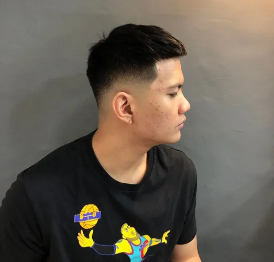 A man with a clean, uniform 9 guard buzz cut, showcasing a short, low-maintenance hairstyle ideal for oval face shapes and thick hair, styled by a professional barber.