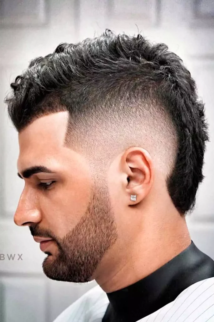 Burst fade wavy mullet haircut with natural waves flowing at the back.