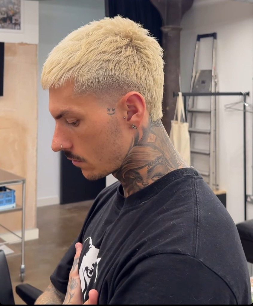 Close-up of blonde buzz cut with lightning bolt design shaved on side, highlighting platinum blonde color and artistry.