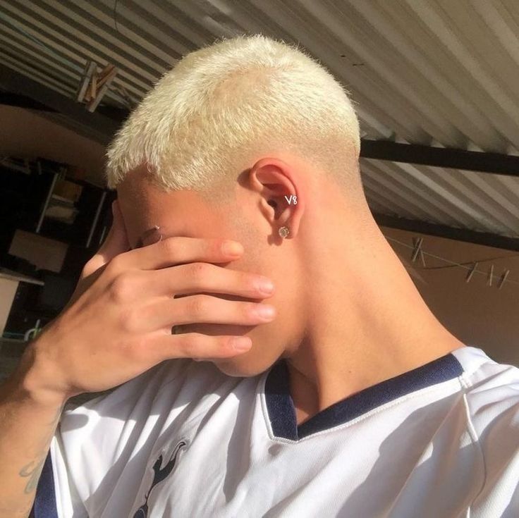 Stylish platinum blonde buzz cut on a man, showcasing crisp edges and vibrant color in a modern barber shop setting.