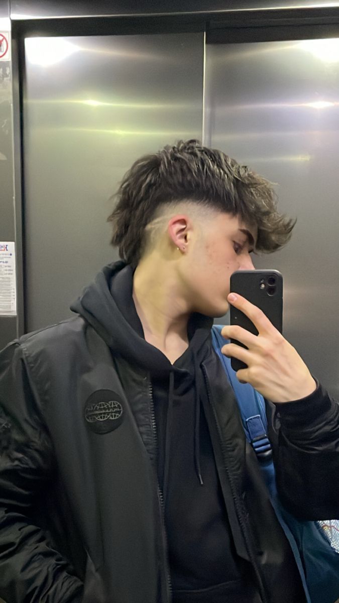 Expert barber trimming a faux mullet with a taper fade for a male client in a trendy barber shop